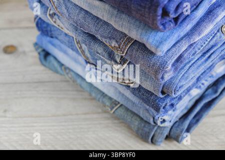 Stack of blue jeans on wooden shelf with copy space. Beauty and fashion clothing concept, selective focus Stock Photo