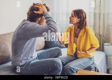 Man and woman are sitting at sofa and arguing. Relationship problems. Stock Photo