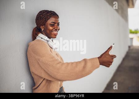 Portrait of young black woman who is having video call on smartphone. Woman using mobile phone outdoor. Stock Photo