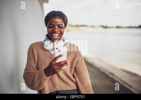 Portrait of young black woman who is having video call on smartphone. Woman using mobile phone outdoor. Stock Photo