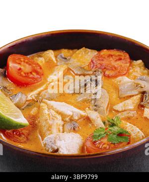 Food, Spicy thai tom yum soup is being served in a brown bowl with chicken, mushrooms, tomatoes, and lime Stock Photo