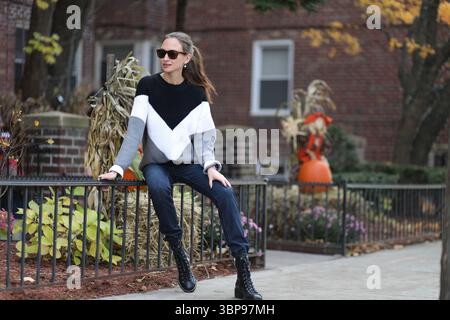 A woman in casual clothes sits next to a building in halloween Stock Photo
