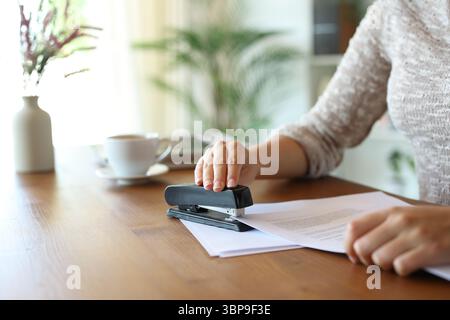 Close up of a woman hand stapling papers on a wooden table at home Stock Photo