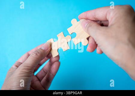 Holding jigsaw puzzle pieces. Against blue background. Matching or cooperation concept. Stock Photo