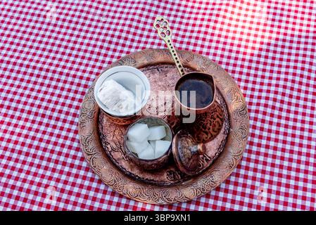 Traditional Turkish coffee brewed in cezve on the sand is served in small mug of sweets Stock Photo