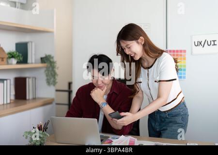 UX UI design session. Professionals analyzing concepts on a laptop and smartphone. Stock Photo