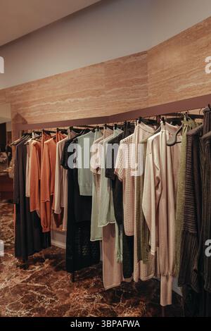 Interior of a luxury boutique with stylish clothes in orange, black and beige colors hanging in a row Stock Photo