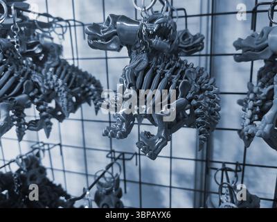 Objects keychains in form of dog skeleton models of toys printed on 3D printer from molten plastic hanging on chain. Concept 3D Printing. Modern 3D Printing additive technology. Blue color Stock Photo
