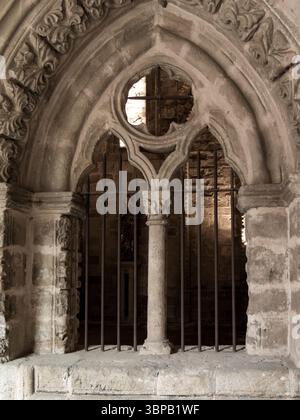 Metal bars protecting a religious statue behind an ornate stone archway, creating a scene of reverence and security within an ancient building Stock Photo