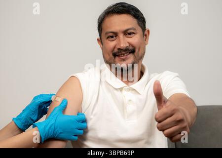 Smiling man getting vaccinated in the arm, showing no fear and promoting vaccine confidence. Stock Photo