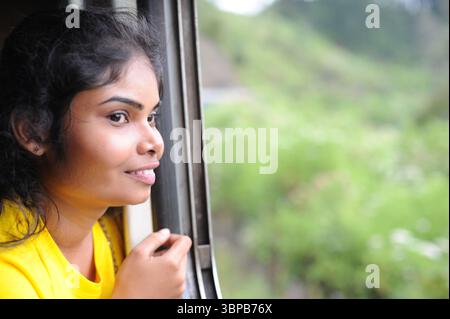 Smiling woman (lady) looking through a window on a train in Sri Lanka Stock Photo