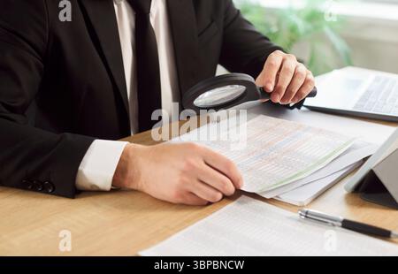 Unrecognizable man dressed formally, using magnifying glass to zoom document Stock Photo