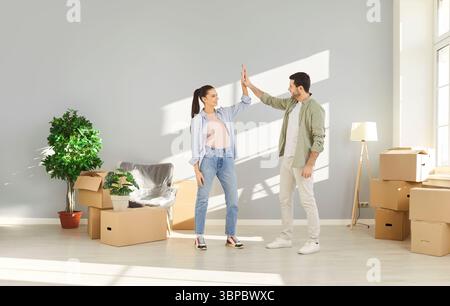 Young couple happy to move to new apartment, gesturing high five as sign of agreement Stock Photo