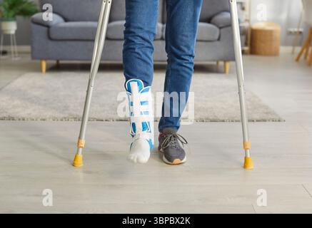 Cropped image of unrecognizable man has broken leg, walking on crutches, wearing fracture fixator Stock Photo