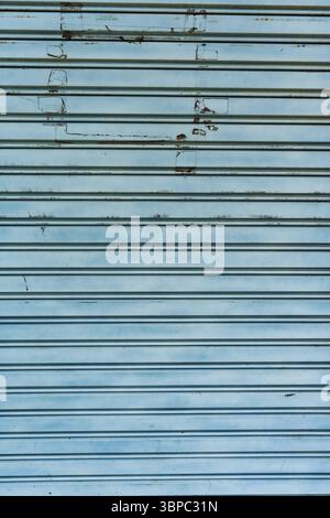 Weathered blue metal roll up shutter gate of garage with scratch and peeling paint as texture background Stock Photo
