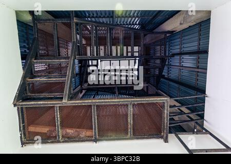 Low angle under inside of metal staircase stacked with rusty steel frame, mesh gruadrails, corrugated metal wall and strong geometric shape in tower Stock Photo
