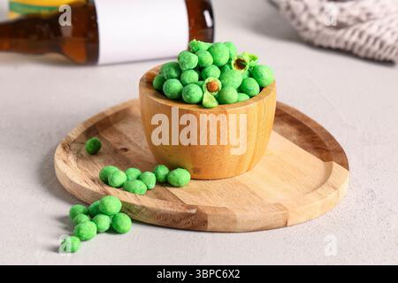 Bowl with wasabi coated crunchy peanuts on light background Stock Photo