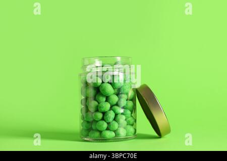 Jar of wasabi coated peanuts on green background Stock Photo