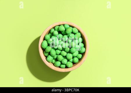 Bowl with wasabi coated peanuts on green background Stock Photo