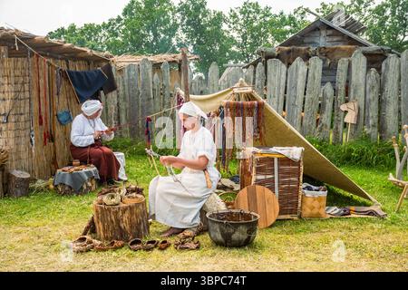 A woman in medieval clothing during a medieval festival making shoes with the leather using an old technique used in the Middle Ages Stock Photo