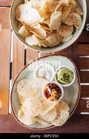 Tortilla chips displayed alongside flavorful dips like guacamole and salsa in a relaxed dining environment. Stock Photo