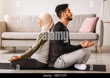 Yoga for Pregnancy and Childbirth. Expecting islamic spouses meditating together at home Stock Photo