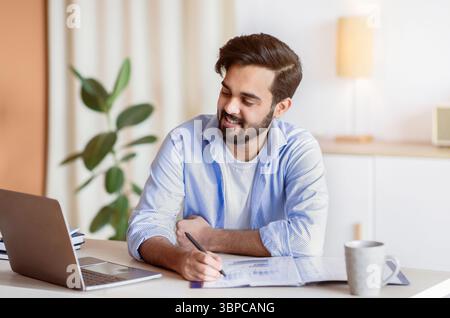 Successful Eastern Entrepreneur Working With Documents And Laptop At Home Office Stock Photo