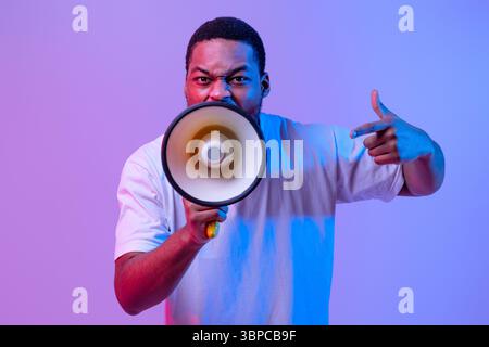 Agressive Black Guy Shouting Into Loudspeaker, Making Announcement And Emotionally Gesturing Stock Photo