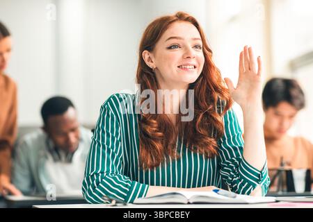 Portrait of smiling female student raising hand at classroom Stock Photo