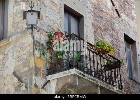044 Wrought-iron railing balcony on a red brickwork wall on Vicolo della Via Nuova, corner with Via di Voltaia nel Corso. Montepulciano-Tuscany-Italy. Stock Photo