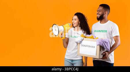 Two Diverse Volunteers Holding Donation Box, Studio Shot, Panorama Stock Photo