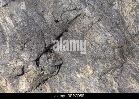 Abstract natural texture, background photo. A highly detailed view of a natural rock surface featuring evident cracks and textured formations. Showcas Stock Photo