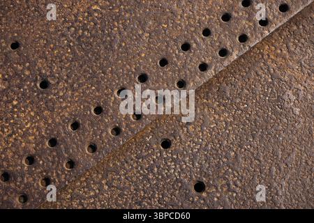 Detailed view of a rusty metallic surface featuring textured patterns and evenly spaced holes. Ideal for industrial or abstract art themes Stock Photo