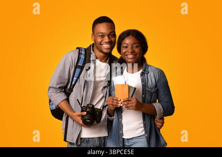 Tourists Couple. Happy african lovers holding passports with tickets and photo camera Stock Photo