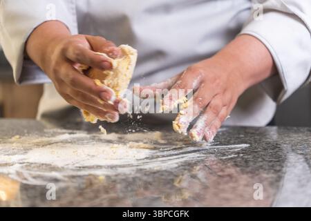 Professional chef preparing dough for baking, kneading ingredients on a marble countertop Stock Photo