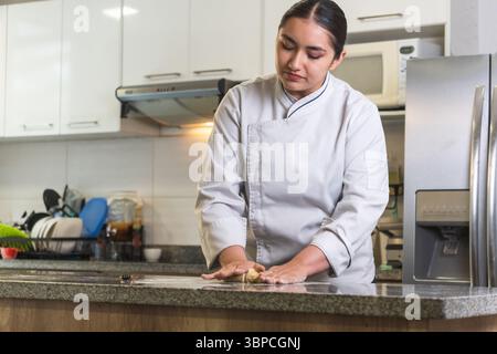 Female chef kneading dough on kitchen counter preparing traditional food Stock Photo