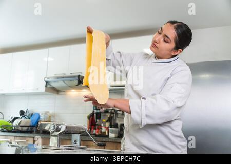 Latin woman chef checking fresh pasta dough in a restaurant kitchen Stock Photo