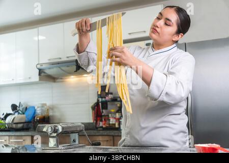 Chef preparing fresh pasta in a modern kitchen using a pasta machine Stock Photo