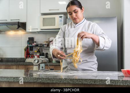 Female chef making fresh homemade pasta in a professional kitchen Stock Photo