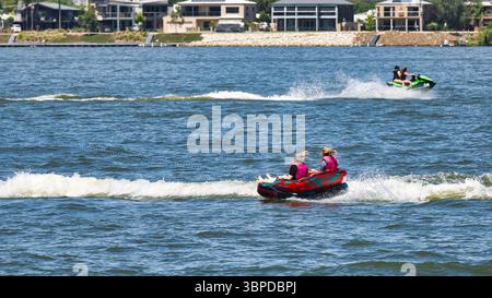 Yarrawonga, Victoria, Australia: 30 January 2025: Closeup of two girls having fun on inflatable tube on Lake Mulwala Stock Photo