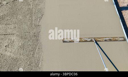 worker leveling concrete slab with long trowel construction worker using a long-handled trowel to smooth freshly Stock Photo