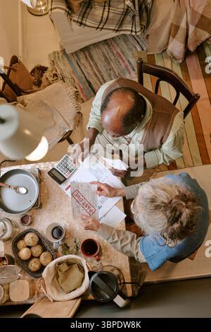 Senior Multiethnic Couple Reviewing Past Due Bills and Facing Financial Hardship Stock Photo