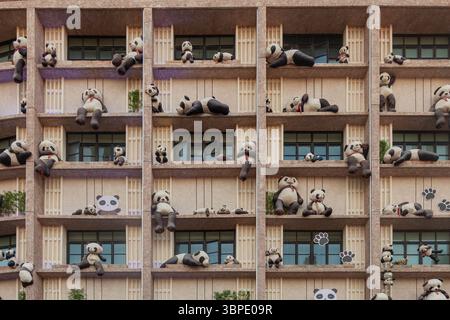 Wall of a multi-story building decorated with toy pandas. Stock Photo