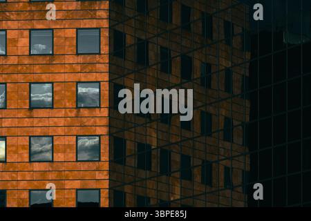 Contrasting reflection of a brick-like facade in a glass building, capturing both surfaces in geometric harmony Stock Photo