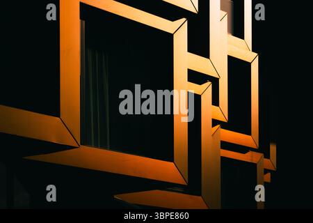 Close-up of modern architectural detail with interlocking orange metal frames in dramatic shadow Stock Photo