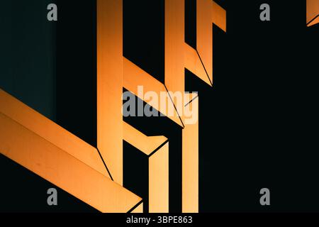 Close-up of modern architectural detail with interlocking orange metal frames in dramatic shadow Stock Photo