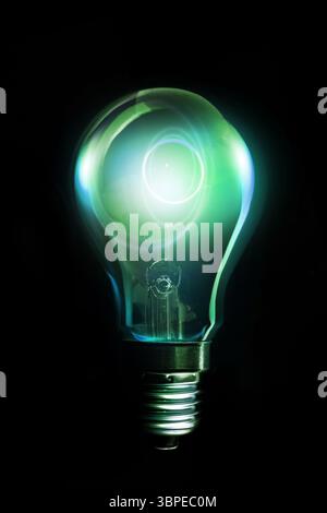 Incandescent light bulb is glowing green with visible filament against black backdrop in 3D render Stock Photo