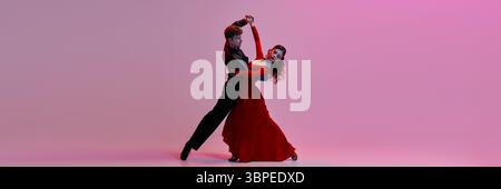 Elegant couple dancing Argentine tango on softly lit pink stage background. Banner Stock Photo