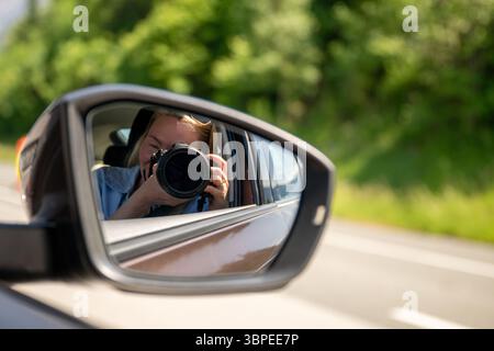 Photographer taking picture reflected in car side mirror on sunny day Stock Photo