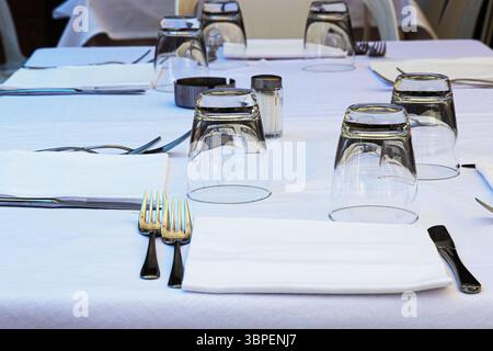 Minimalist dining table setting with white tablecloth, cutlery, glassware, ready for guests Stock Photo